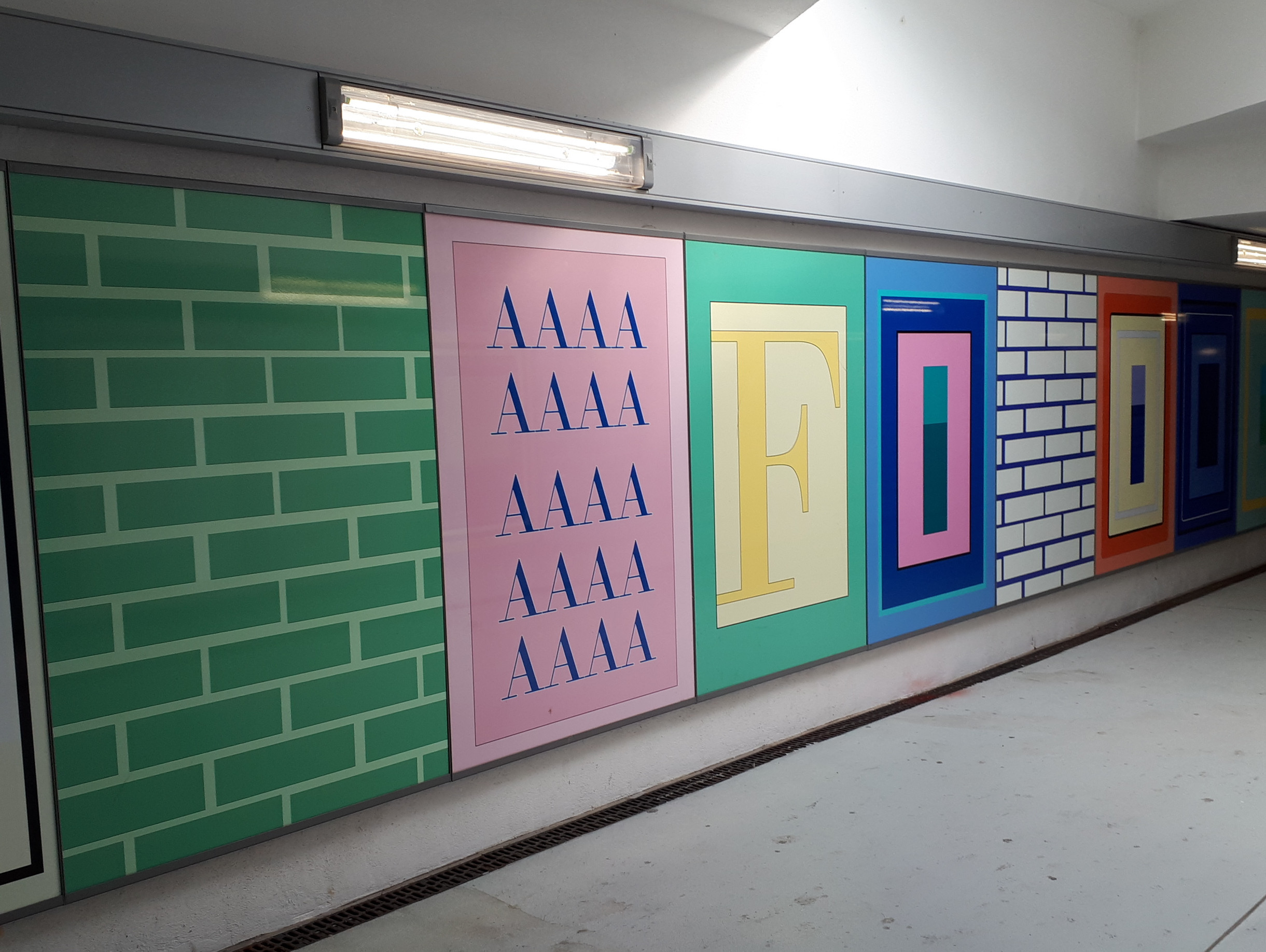 One corridor wall is decorated with colourful panels, including green and white brick patterns, repeated "AAAA" letters in pink and large stylised letters with the word "FOOD" in yellow, red, blue and orange.