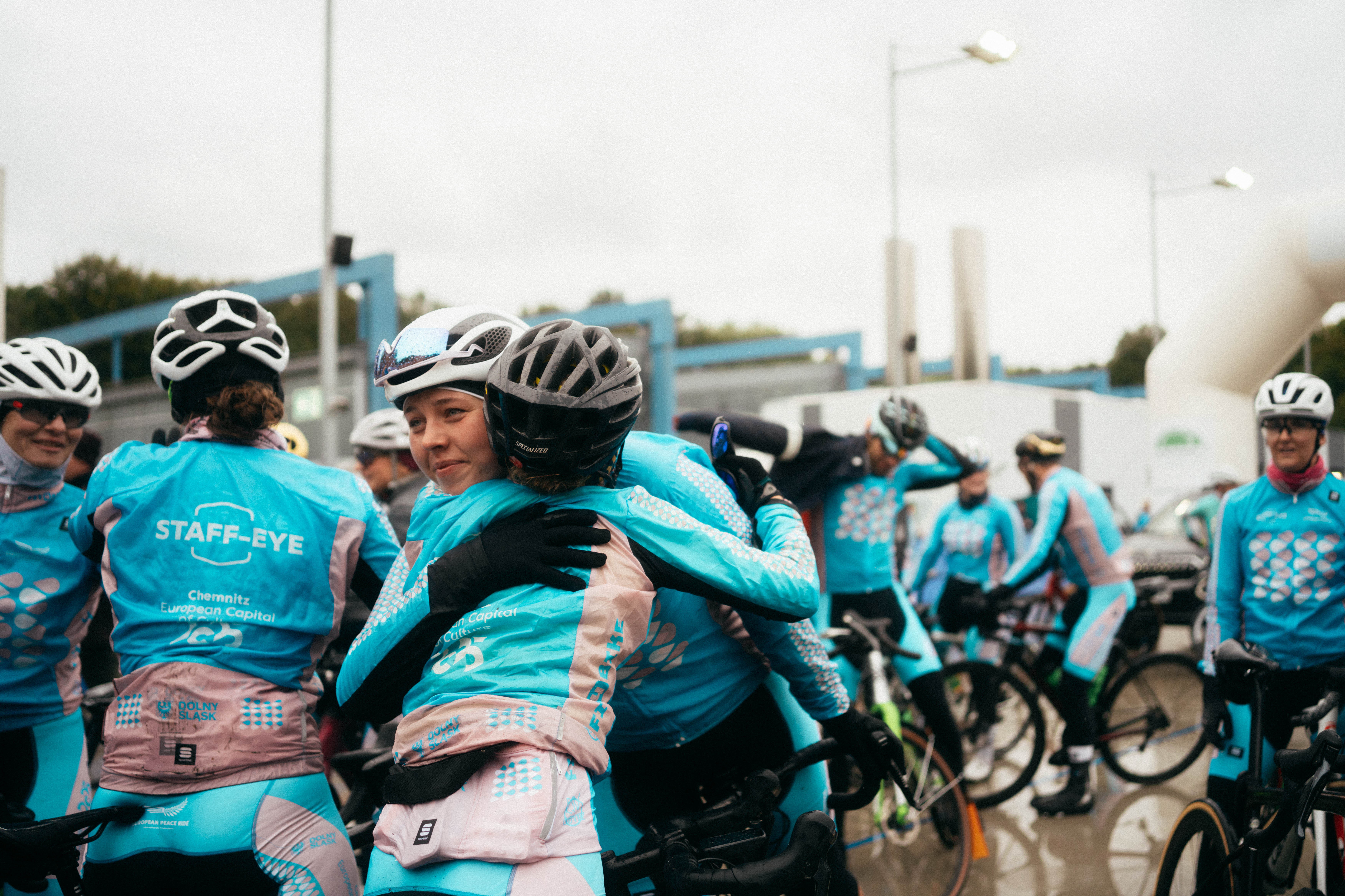 A group of people wearing helmets hug each other.